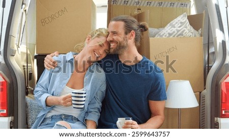 Couple Taking A Break In Back Of Removal Truck With Packing Boxes On Moving Day