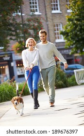 Couple Taking Dog For Walk In City Park