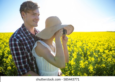 Couple taking picture from camera in mustard field on a sunny day - Powered by Shutterstock