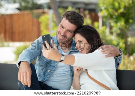couple taking selfie portrait picture sitting bench outdoor city street