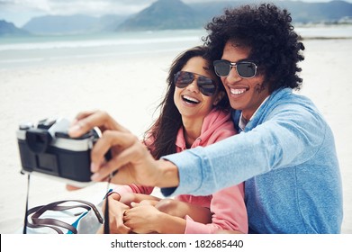 couple taking selfie self portrait at the beach with retro hipster camera