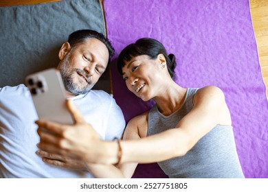 Couple taking a selfie while relaxing on yoga mats - Powered by Shutterstock