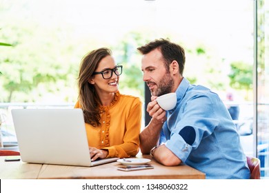 Couple Talking At Cafe Using Laptop And Drinking Cofee