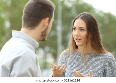 Couple talking outdoors in a park with a green background