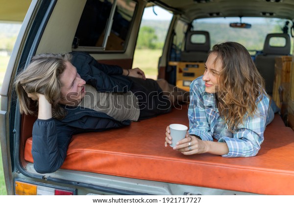 Couple talking relaxing in the camp car ,drinking\
coffee and talking in the camp car, laying down in the camp car\
,Summer traveling\
concept