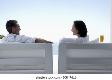 Couple talking, sitting on lounge chairs, outdoors - Powered by Shutterstock