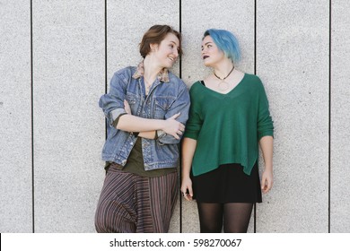 Couple Of Teen Gay Women Looking To Each Other Isolated On A Grey Wall