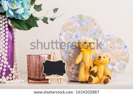 A couple of textile bears, a vase of flowers, a candlestick and other nice things on the dresser in the bedroom