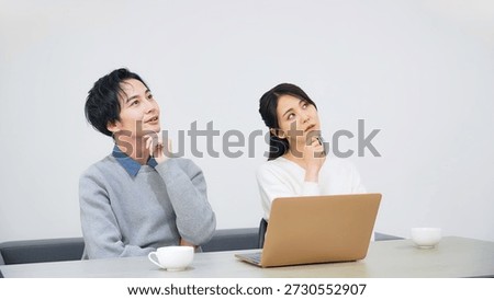 A couple thinking while looking at a laptop in a room