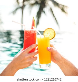 Couple Toasting With Cocktails By The Pool