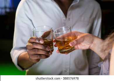 Couple Toasting Their Whisky Glasses In Bar