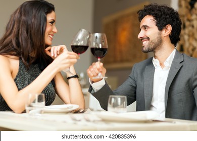 Couple toasting wineglasses in a luxury restaurant. Focus on the woman