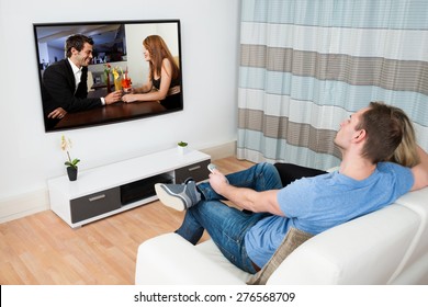 Pareja Sentada En Sofa Viendo Película En Televisión