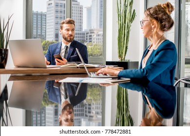Couple of top managers working with laptops and documents sitting at the luxury office interior with beautiful view on the skyscrapers - Shutterstock ID 778472881