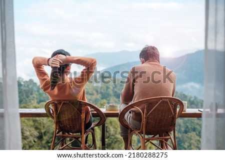 Couple tourist drinking coffee and eating breakfast against mountain view at countryside home or homestay in the morning. Vacation, together travel, honeymoon, blogger, journey and trip concept