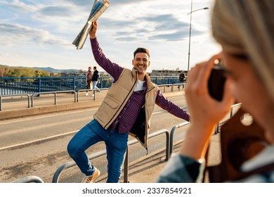 couple tourist in sightseeing in city using a map, woman taking pictures with camera of her partner