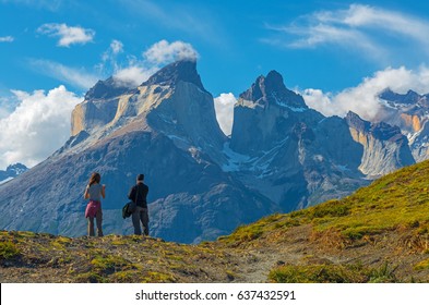 A couple of tourists / backpackers enjoying the view of the granite peaks in the Torres del Paine national park at sunset near Puerto Natales in Patagonia, Chile.