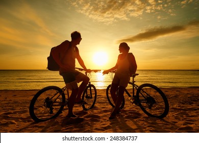 Couple tourists with Bicycles Watching Sunset. Summer Nature Background with Beautiful Sky and Sea. Active Leisure Concept.