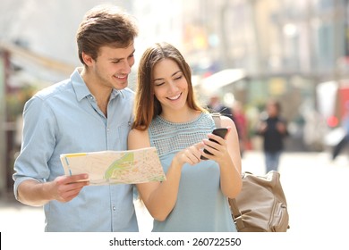 Couple of tourists consulting a city guide and smartphone gps in the street searching locations - Powered by Shutterstock