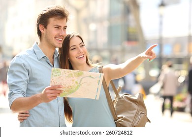 Un par de turistas consultando a una guía de la ciudad buscando lugares en la calle y señalando