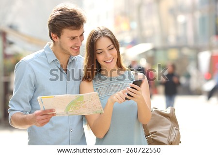 Couple of tourists consulting a city guide and smartphone gps in the street searching locations