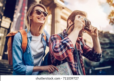 Couple of tourists is exploring new city together. Smiling and making photo on a retro camera. - Shutterstock ID 711039727