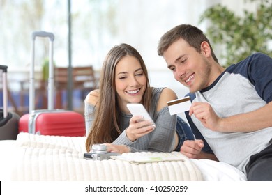 Couple Of Tourists Ready For Travel Booking Hotel On Line With Credit Card And Mobile Phone On The Bed 