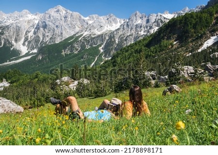 A couple of tourists rest on a meadow in the mountains of Albania. Mountains on the north Albania