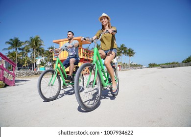 Couple Of Tourists Riding Bike In Miami Beach