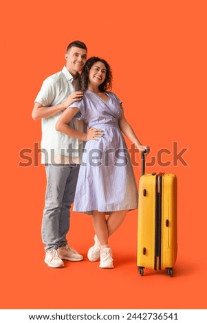Couple of tourists with suitcase on orange background