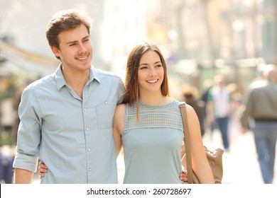 Couple Of Tourists Taking A Walk In A City Street Sidewalk In A Sunny Day