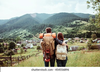 A couple of tourists in time of trip steel and admire the beautiful mountain scenery. The guy hugs the girl. The concept of love, tenderness and recreation