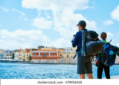 Couple Tourists Walking On The Waterfront Of Chania Bay Backround, Crete, Greece