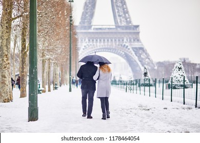 Couple of tourists walking in Paris under umbrella on a day with heavy snow. Unusual weather conditions in Paris - Powered by Shutterstock