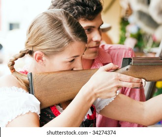Couple in traditional German or Bavarian costume doing some target shooting at a gallery