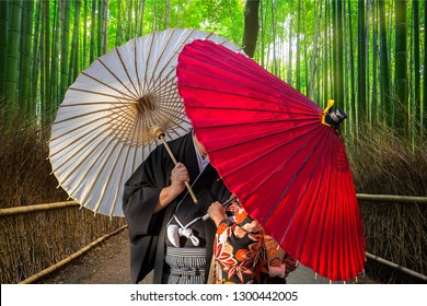 Couple With Traditional Japanese Umbrellas Posing At Bamboo Forest In Arashiyama