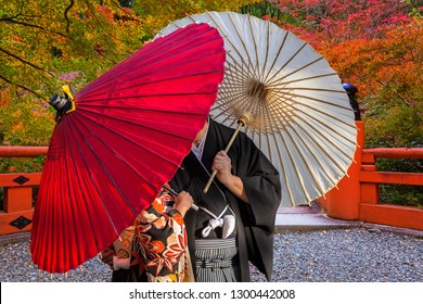 Couple With Traditional Japanese Umbrellas Posing At Autumnal Park In Kyoto