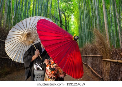 Couple With Traditional Japanese Umbrellas Posing At Bamboo Forest In Arashiyama