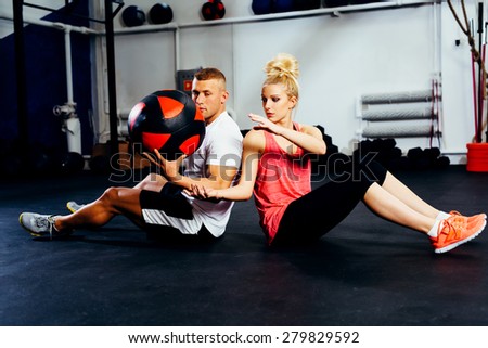 Couple training with exercise ball at gym