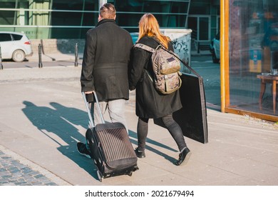 A Couple With Travel And Black Huge Thin Nylon Artist Portfolio Bag Walking Through The City's Street. Art. Drawling. Storage