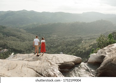 Couple of  travel bloggers explore beautiful places in Sri Lanka island. Man ad woman in a Sunny day in the Waterfall falls from the mountain cliff to the jungle, serene landscape of Diyaluma falls