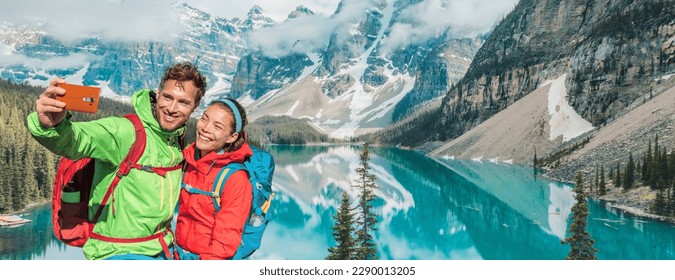 Couple travel selfie banner landscape happy hikers in winter alps lake view. Asian woman, Caucasian man using mobile phone - Powered by Shutterstock