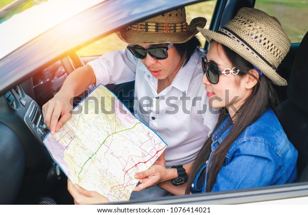 Couple of traveler sitting in the car\
and using a local map  for find the way during holiday.Young couple\
tourist enjoying on vacation. selective\
focus.