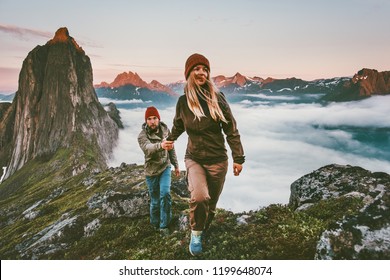 Couple travelers holding hands hiking together in Norway travel healthy lifestyle concept active vacations outdoor Segla mountain sunset landscape