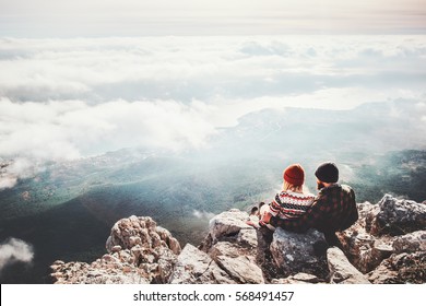 Couple Travelers Man And Woman Sitting On Cliff Relaxing Mountains And Clouds Aerial View  Love And Travel Happy Emotions Lifestyle Concept. Young Family Traveling Active Adventure Vacations