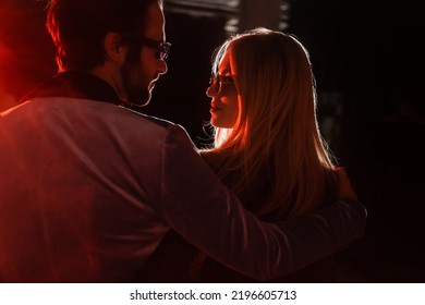 Couple In Trendy Eyeglasses Looking At Each Other At Night Party In Darkness With Light