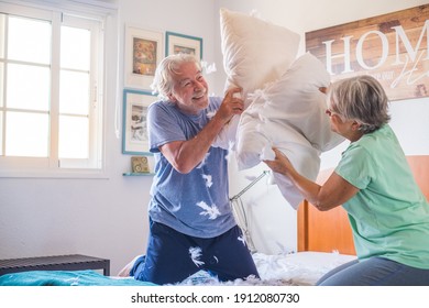 couple of two happy seniors having fun playing together on the bed at home fighting with pillows enjoying - pillows war indoors in the morning - Powered by Shutterstock