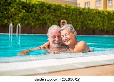 Couple of two happy seniors having fun and enjoying together in the swimming pool smiling and playing. Happy people enjoying summer outdoor in the water