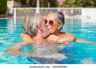 Couple of two happy seniors having fun and enjoying together in the swimming pool smiling and playing. Happy people enjoying summer outdoor in the water