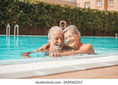 Couple of two happy seniors having fun and enjoying together in the swimming pool smiling and playing. Happy people enjoying summer outdoor in the water - Powered by Shutterstock